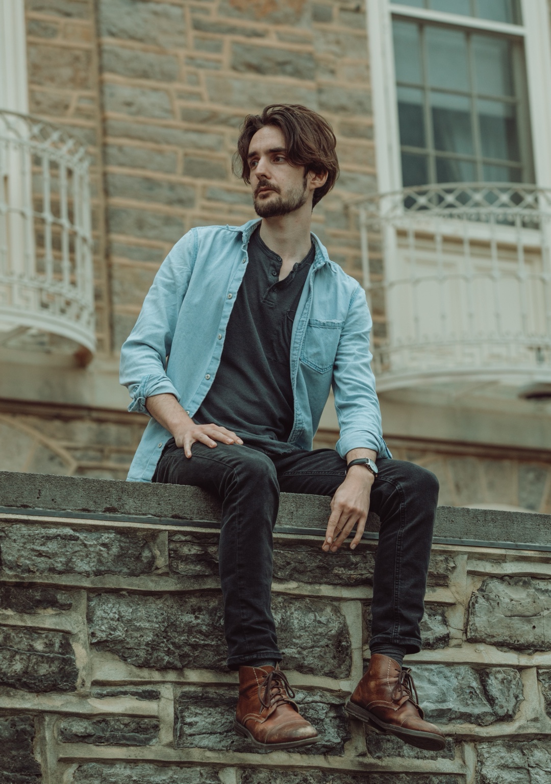 Man seated on a stone wall in front of a historic building